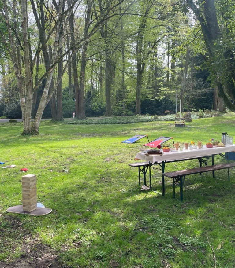 Set-up für das Parkspiele-Teamevent in Düsseldorf: Spielstationen im Grünen mit Verpflegungstisch, Snacks und Frühlingsdeko